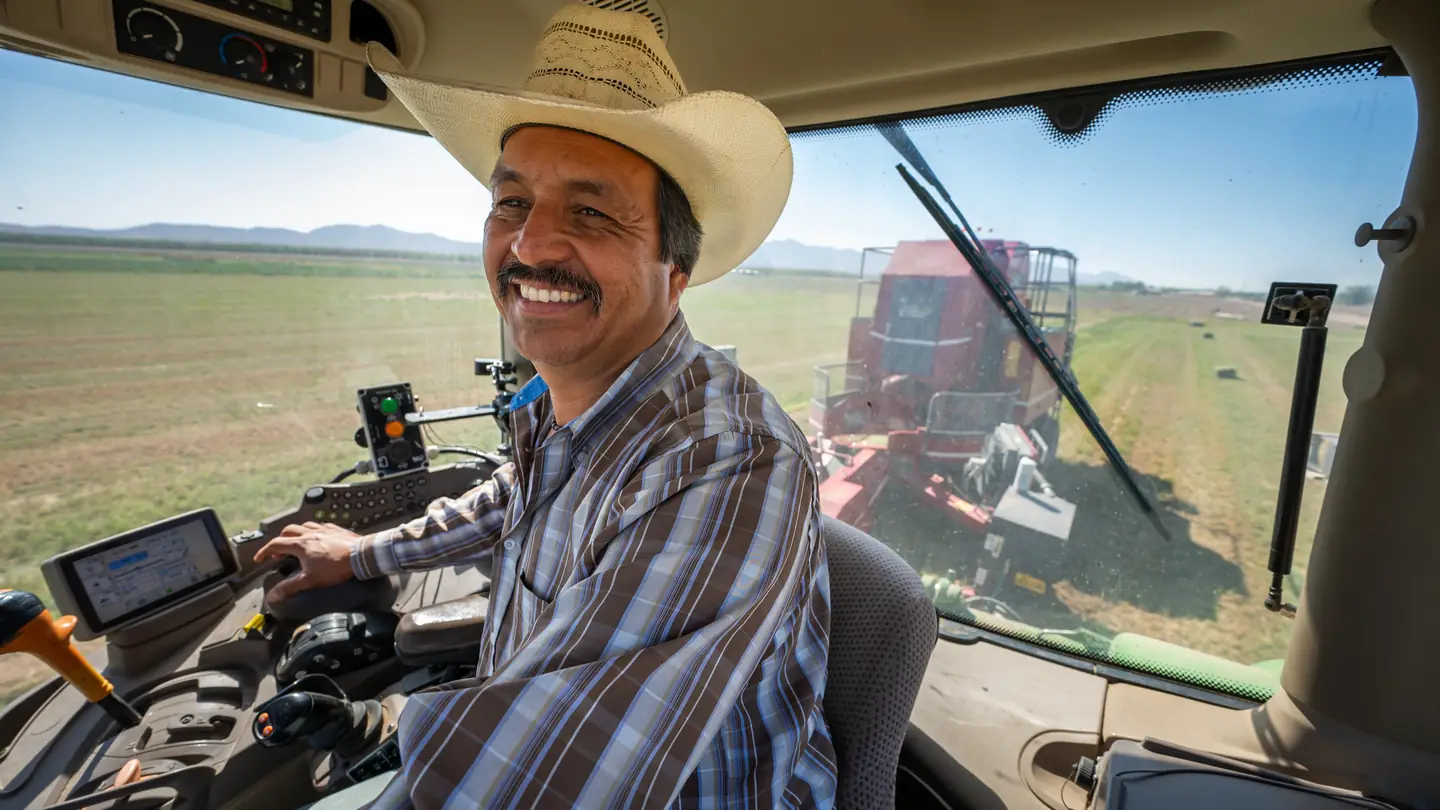 A farmer in a tractor cab with the guidance displays beside him