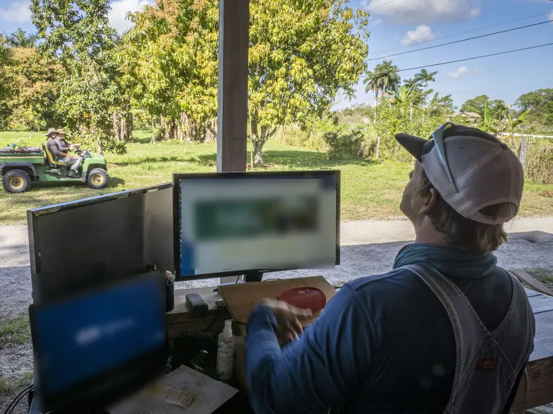 A farmer working at a computer in an open-air farm office