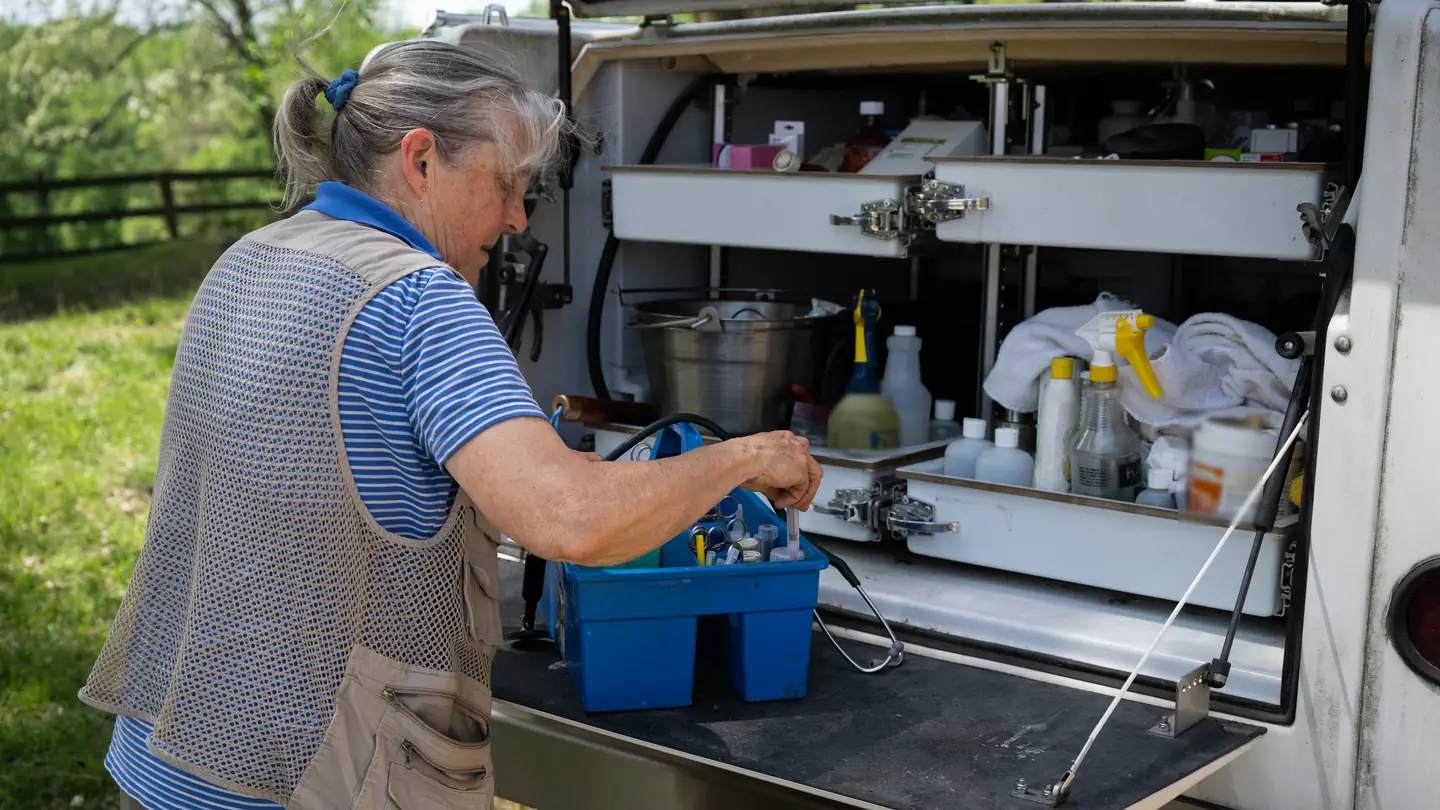 A veterinarian reaching into the supply box built into the back of her truck